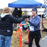 Delcenia Cosman / Homer News
Homer High School junior and track team member Reilly Sue Baker (left) presents Simone Owens (right) with a sunflower in honor of Mothers Day after Owens crossed the finish line of the annual Migration Run on Sunday, May 10<ins>, 2026</ins>, on the Homer Spit Trail<ins> in Homer, Alaska</ins>.