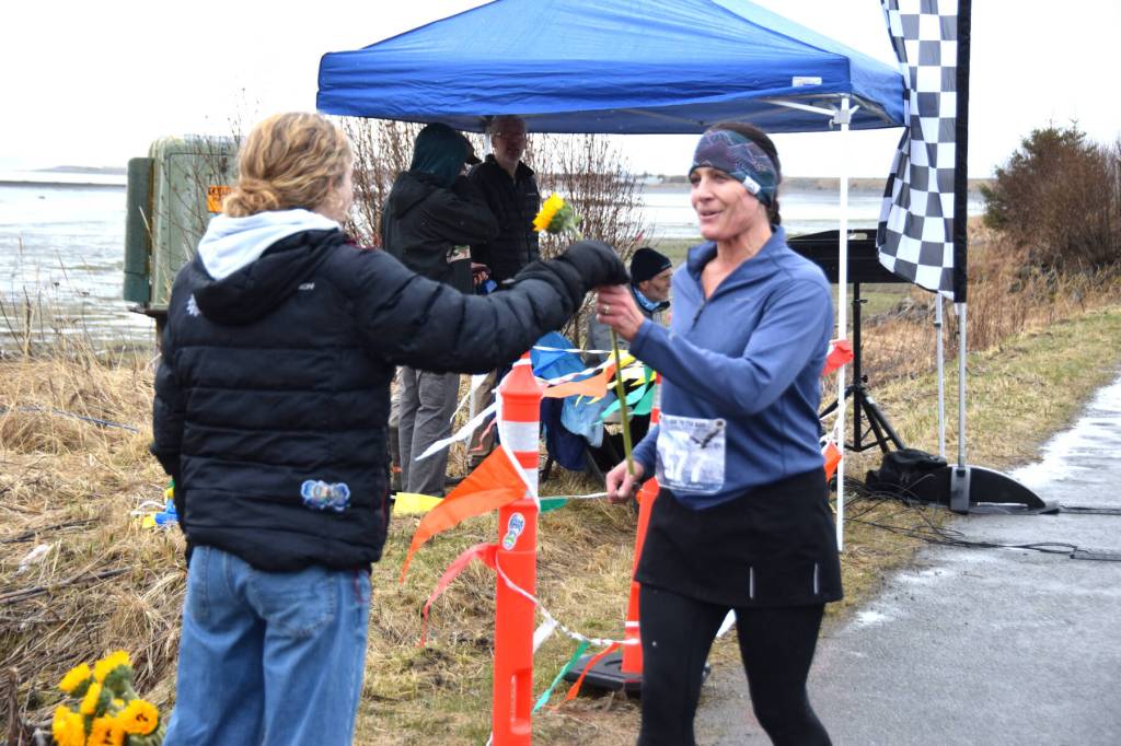 Delcenia Cosman / Homer News
Homer High School junior and track team member Reilly Sue Baker (left) presents Simone Owens (right) with a sunflower in honor of Mothers Day after Owens crossed the finish line of the annual Migration Run on Sunday, May 10<ins>, 2026</ins>, on the Homer Spit Trail<ins> in Homer, Alaska</ins>.
