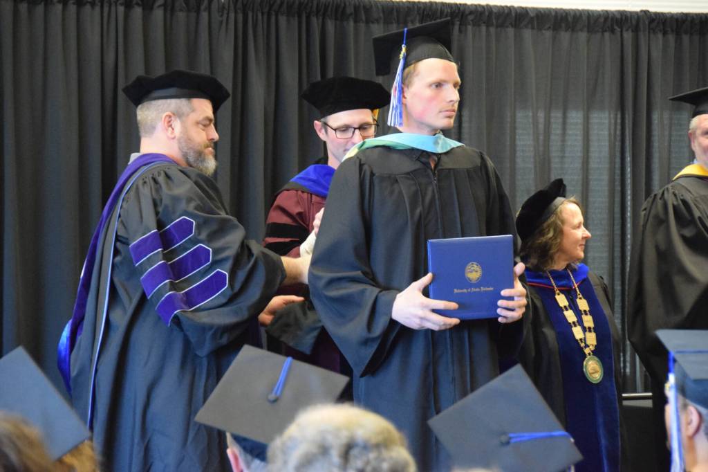 Casey Fetterhoff graduates with his masters degree and is hooded by University of Alaska Regent Joe Crum and University of Alaska Anchorage Vice-Chancellor Aaron Dotson during a commencement ceremony held Wednesday, May 6<ins>, 2026,</ins> at Kachemak Bay Campus<ins> in Homer, Alaska</ins>. (Delcenia Cosman/Homer News)