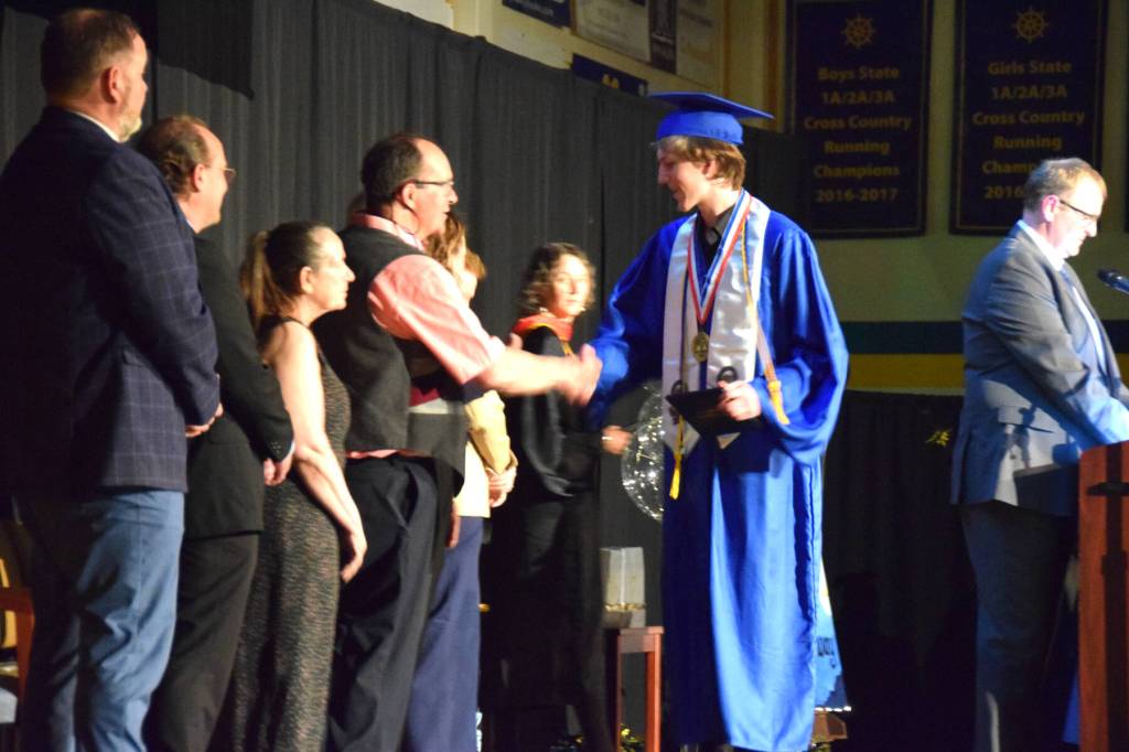 Homer High School Class of 2026 valedictorian Lukas Renner (center) shakes hands with Kenai Peninsula Borough School District representatives as he receives his diploma in a commencement ceremony on Monday, May 18<ins>,</ins> <ins>2026</ins>, in the Homer High School Alice Witte Gymnasium<ins> in Homer, Alaska</ins>. (Delcenia Cosman/Homer News)
