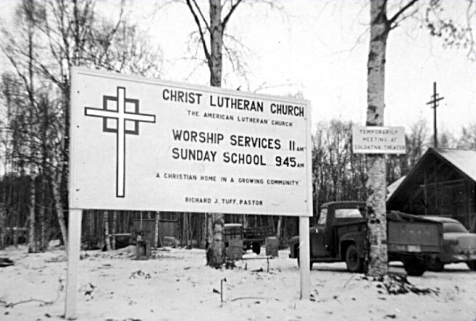 Signs of the times at Soldotnas Lutheran Church, which was still under construction in the early 1960s. The small sign on the birch tree reads, Temporarily Meeting at Soldatna Theater. (Photo from the Kenai Peninsula College photo archive)