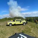 A column of smoke rises above Division of Forestry & Fire Protection vehicles in Sterling, Alaska. (Photo courtesy of DFFP)